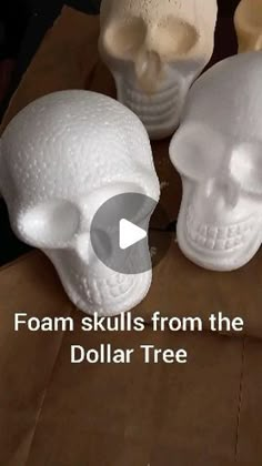 three white skulls sitting next to each other on top of a cardboard box with the words foam skulls from the dollar tree