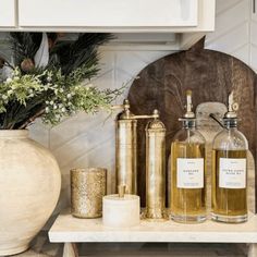 some bottles are sitting on a table with candles and flowers in the vase next to them