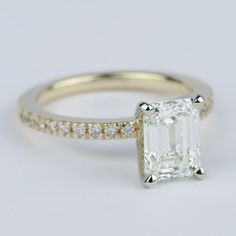 an engagement ring with a large emerald cut diamond in the center and pave set side stones