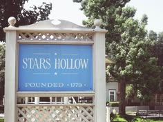 a sign for stars hollow is in front of some trees and benches on the grass