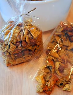 two bags of chex mix sitting on top of a table next to a bowl