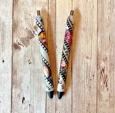 two pens sitting on top of a wooden floor next to each other with different designs