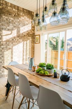 a dining room table that has some fruit on it and lights hanging from the ceiling