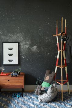 a space themed bedroom with black walls and stars in the sky, as well as a teddy bear