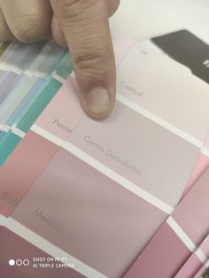 a person's finger is pointing at some color swatches