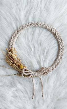 a braided rope bracelet with dried flowers on white furnishish background, top view