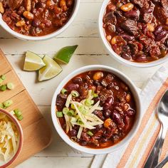 three bowls filled with chili and beans next to a cutting board