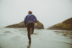 a man walking on the beach with his feet in the water