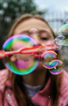 a girl blowing bubbles in front of her face