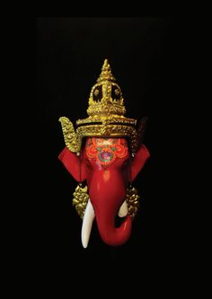 an elephant statue with gold decorations on its head and tusks, against a black background