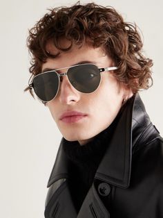 a young man with curly hair wearing sunglasses and a black leather jacket, looking at the camera