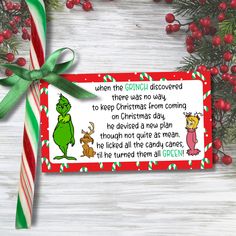 a grinch christmas gift tag with candy canes and holly branches on the table