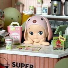 there is a small doll sitting on the counter next to other toys and items in front of it