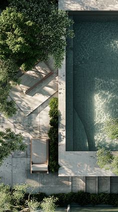 an aerial view of a swimming pool surrounded by trees and bushes, with a bench in the foreground