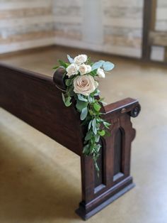 a wooden bench with flowers and greenery on it