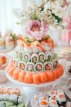 sushi wedding cake with flowers on top and other desserts in the back ground