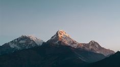 the mountains are covered in snow at sunset or dawn, with no clouds on them