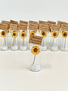 there are many sunflowers in glass vases with place cards on the top