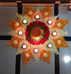 a circular arrangement of flowers and candles on the floor in front of a ceiling light