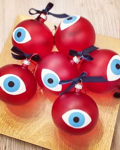 red ornaments with blue eyes are on a wooden board