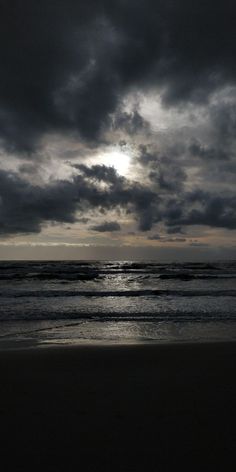 the sun is shining through dark clouds over the ocean