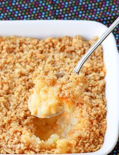 a close up of a spoon in a casserole with crumbs on it