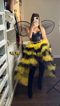 a woman taking a selfie in a yellow and black dress while wearing a bee costume