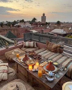 an outdoor table with food and drinks on it in front of a cityscape