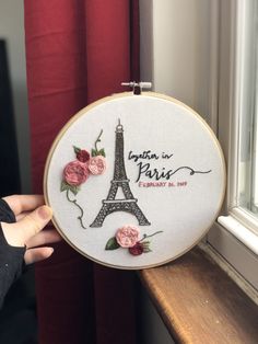 someone is holding up a embroidery project with the eiffel tower in paris