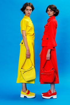 two women in red and yellow dresses standing next to each other with handbags on their shoulders