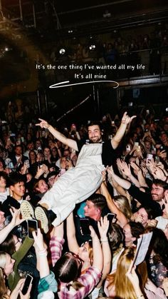 a man is in the middle of a crowd with his arms up and hands raised