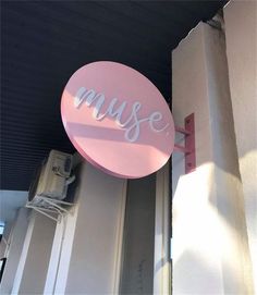 a pink sign hanging from the side of a building that says,'music '