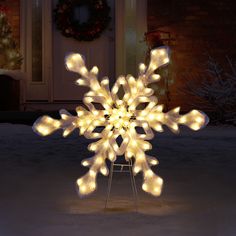 a lighted snowflake in front of a house