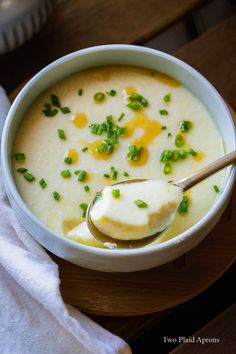 a white bowl filled with soup on top of a wooden table next to a napkin