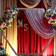 the stage is decorated with floral arrangements and draping for an elegant wedding ceremony