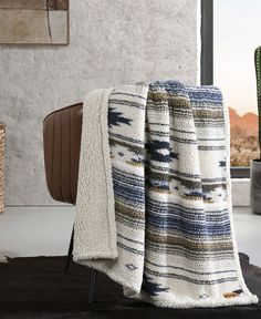 a blanket that is sitting on top of a chair in front of a window with a cactus