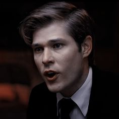 a man in a suit and tie making a weird face with his tongue sticking out