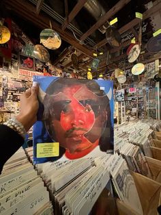 a person holding up a record in front of a wall full of records