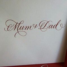 the word mum and dad written in cursive writing on a white card next to a red envelope