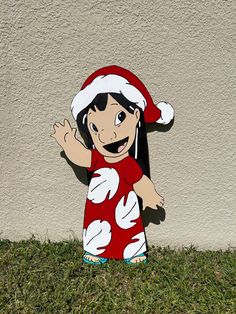 a cardboard cutout of a child wearing a santa hat and red dress standing in the grass