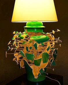 a green table lamp sitting on top of a night stand next to a yellow light