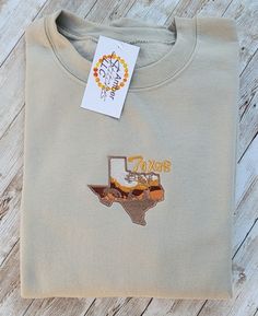 Texas state graphic embroidered on sweatshirt. Embroidered Patch Tops For Streetwear In Fall, Embroidered Fall College T-shirt, Embroidered Graphics T-shirt For College In Fall, Fall College T-shirt With Embroidered Logo, College T-shirt With Embroidered Logo For Fall, Casual Embroidered Sweatshirt For Fall, Fall T-shirt With Embroidered Logo In Relaxed Fit, Fall College Embroidered T-shirt, Embroidered Text T-shirt For College In Fall