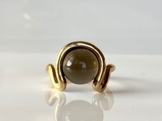 Bold, modern and striking in its distinctive design and craftsmanship, this earthy grey moonstone round cabochon ring is a contemporary alternative to the traditional cocktail ring. Slip this ring on your finger when you need a bold, statement-making piece of jewelry. 9K solid yellow gold  Grey moonstone 11mm Available size 18.4 Follow us on Instagram: https://www.instagram.com/missionewyork/ Modern Yellow Gold Round Moonstone Ring, Modern Yellow Gold Moonstone Ring, Modern Cabochon Moonstone Ring For Formal Occasions, Modern Round Cabochon Moonstone Ring, Modern Cabochon Moonstone Ring, Grey Moonstone, Gold Statement Ring, Wave Ring, Solid Gold Chains