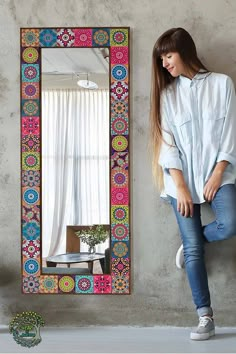 a woman standing in front of a colorful mirror