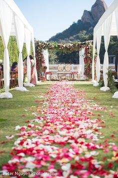 the aisle is decorated with flowers and white draping for an outdoor wedding ceremony