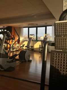 there are many treadmills in the gym with windows looking out on the city