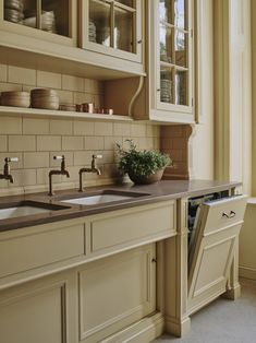 a kitchen with white cabinets and brown counter tops, an open dishwasher in the middle