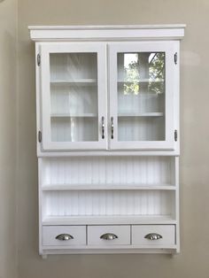 a white hutch with two drawers and three doors on the front, in a room