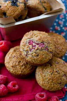 some raspberry muffins are sitting on a red cloth next to fresh raspberries