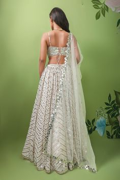 Ivory,off white georgette lehenga with attached cancan and chevron embroidery in sequins, mirror and patra. Comes with embellished padded blouse and floral bordered dupatta.
Component: 3
Pattern: Embroidery
Type Of Work: Sequins, Mirror, Patra
Neckline: V Neck
Sleeve Type: Sleeveless
Fabric: Lehenga and Blouse: Georgette, Dupatta: Net
Color: Ivory
Other Details: 
Attached lining
Sequins, mirror and patra work
Note: The neckpiece worn by the model is not for sale
Occasion: Bride,Wedding - Aza Fas White Cutdana Dress For Reception, White Cutdana Wedding Dress, White Georgette Gown For Reception, White Cutdana Dress For Party, White Cutdana Party Dress, White Georgette Sharara For Wedding, White Georgette Choli With Sheer Dupatta, White Georgette Gown With Sheer Dupatta, White Georgette Wedding Gown